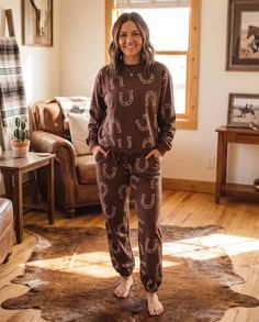 Woman in brown loungewear with a horseshoe pattern standing on a cowhide rug