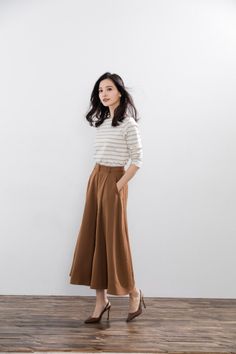 Woman with long hair wearing a striped shirt and wide leg pants indoors
