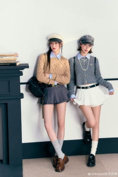 Two women in school uniform-style outfits with berets posing indoors