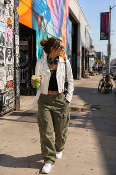 Woman in a white jacket and cargo pants walking on an urban street