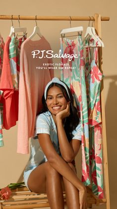 Smiling woman in pajamas and a headband sitting next to a clothing rack