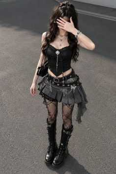 Woman in gothic attire with a black corset and mini skirt covering her face