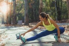 Woman in athletic wear stretching outdoors with a kettlebell nearby