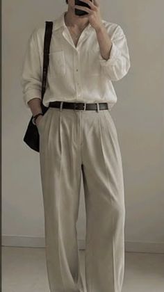 Person in a white shirt and wide leg pants taking a mirror selfie