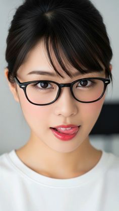 Woman with black hair and glasses licking her lips in a close-up portrait