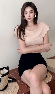 Woman with long hair wearing a ruffle top and black skirt, sitting indoors