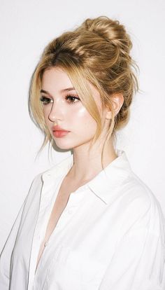 Woman with blonde hair in a messy bun wearing a white shirt