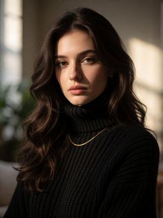 Woman with long dark hair wearing a black turtleneck and gold chain indoors