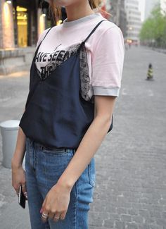 Person in blue jeans and a pink t-shirt with a lace top on a street