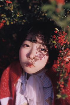 Person with short hair and red berries, with leaf shadows on their face