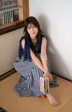 Woman in a gingham dress sitting on a tatami mat with books