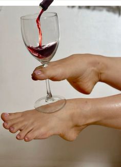 Red wine being poured into a glass held by a foot