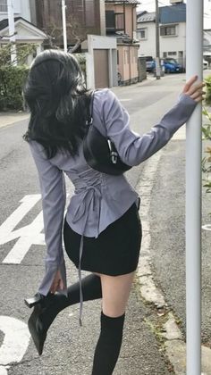 Woman in a corset top and mini skirt posing on a street
