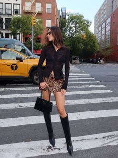 Woman in a sheer top and leopard print skirt on a city street