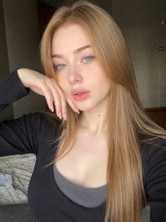 Woman with long blonde hair and blue eyes wearing a black shirt over a gray top