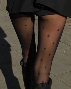 Person wearing black tights and a short skirt with boots outdoors