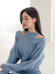 Woman with long dark hair wearing a blue top with shoulder cut outs