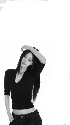 Woman with long hair in a black top and jeans posing in a studio