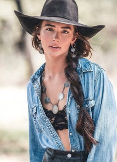 Woman in a cowboy hat and unbuttoned denim shirt with a long braid