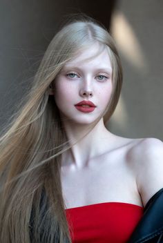 Woman with long blonde hair, red lipstick, and freckles wearing a red top