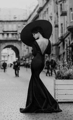 Woman in a black dress with an open back and wide brim hat on a street
