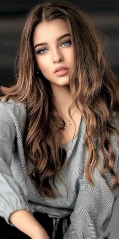 Woman with long brown hair wearing a plaid shirt and a necklace