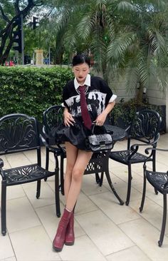 Woman in a black t-shirt, mini skirt, and red boots posing outdoors
