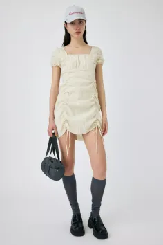 Woman in a light mini dress, baseball cap, and knee-high socks holding a small bag