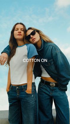 Two women in denim clothing posing outdoors against a blue sky