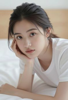 Woman in a white t-shirt resting her chin on her hand indoors