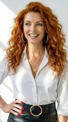 Woman with red curly hair and a white shirt smiling