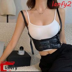 Woman in a black corset over a white tank top with exposed midriff