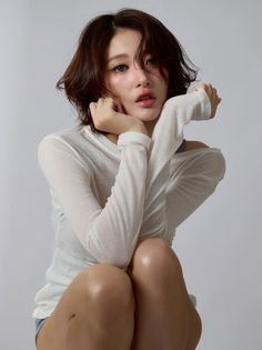 Woman with short brown hair wearing a white long-sleeve shirt with an exposed shoulder