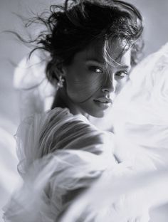 Woman with windblown hair and sheer fabric in a dramatic black and white portrait