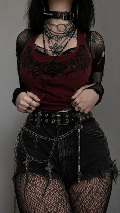 Person in gothic attire with layered necklaces and fishnet clothing