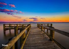Wooden pier extending into calm water under a vibrant sunset sky