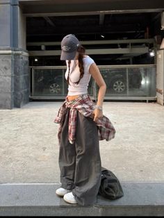 Woman in a crop top, baggy pants, and a plaid shirt tied around her waist