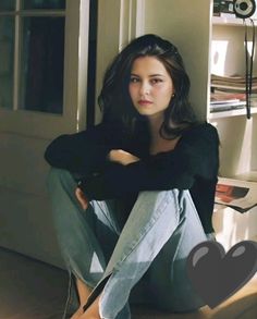 Woman with long dark hair sitting on the floor in soft indoor lighting