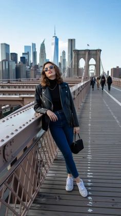 Woman in a leather jacket and sunglasses posing on the Brooklyn Bridge