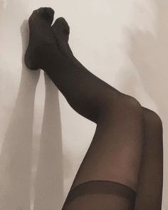 Legs in black stockings against a white wall with shadows