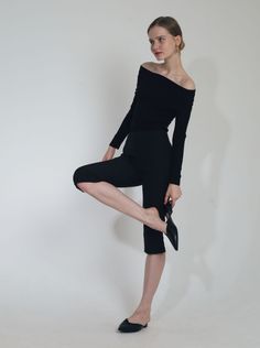 Woman in a black off-shoulder top and cropped pants on a white background