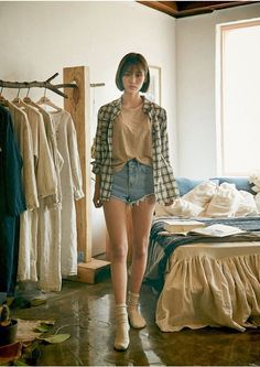 Woman in a plaid shirt and denim shorts standing in a rustic room