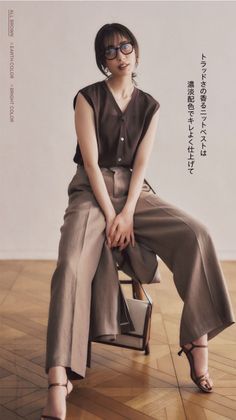 Woman in a brown top and wide leg pants sitting on a chair indoors