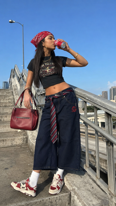 Woman in a crop top and wide leg jeans drinking from a can outdoors