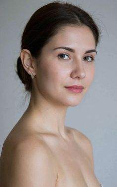 Woman with dark hair in an updo wearing earrings, looking at the camera