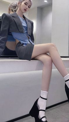 Woman in a cropped blazer and mini skirt with light purple hair