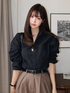 Woman with long brown hair wearing a black shirt and brown pants indoors