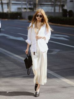 Woman with long blonde hair and sunglasses walking on a street