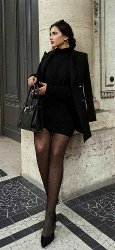 Woman in a black dress and polka dot tights holding a handbag outdoors
