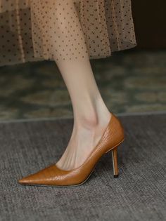 Close up of a foot in a brown pointed-toe heel with a polka dot dress